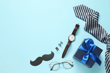 Paper mustache, gift box and men accessories on light blue background, flat lay with space for...