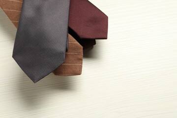 Different neckties on white wooden table, top view. Space for text