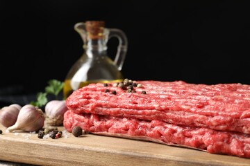 Raw ground meat, peppercorns and garlic on table, closeup