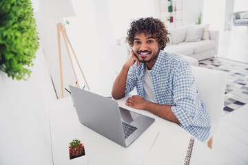 Photo of cheerful positive guy dressed plaid shirt writing emails modern device indoors room home...