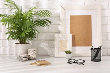Stylish office workplace. Decor elements, glasses and stationery on white table near brick wall