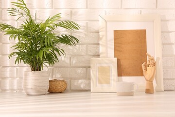 Stylish office workplace. Decor elements, plant and cup on white table near brick wall
