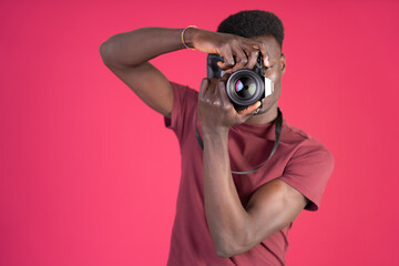 A man wearing a red shirt is taking a picture with a camera