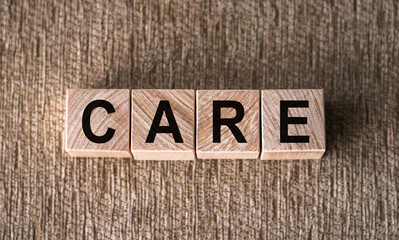 Fototapeta premium Wooden blocks are arranged on a carpet to spell the word care. The blocks are made of wood with individual letters on them.