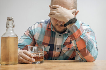 Addicted and drunk man at the table with a glass of alcohol drink, whiskey or brandy, alcoholism...