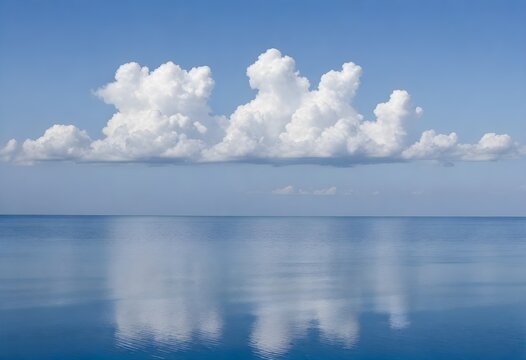 Calm blue ocean with white clouds reflected on the water surface