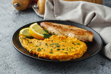 delicious mashed sweet potatoes and fried chicken breast on a light stone background