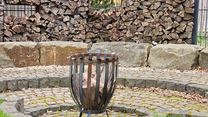 A large fire pit with wood in it sits in front of a stone wall