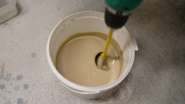 Mixing paint in a bucket. A bucket of hedgehog paint mixing in motion. A painter mixes paint using a bucket mixer.