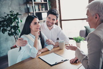 Portrait of young couple chatting meeting realtor lady desk loft interior office indoors