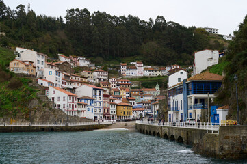 Fototapeta na wymiar Cudillero is a small, picturesque fishing port nestled on the side of a mountain. Its hanging houses stand out with eaves and brightly colored windows that are located in a steep horseshoe of cliffs