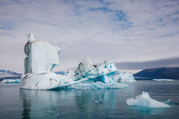 Jokulsarlon glacier lagoon in summer, with melted icebergs, spectacular glacial tongue, and sky in...