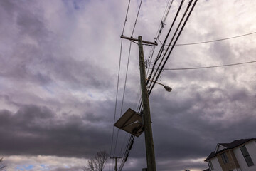 Close-up view of high-voltage power lines running on wooden poles alongside a street in New Jersey....