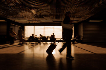 People at an airport terminal, walking with luggage and sitting, waiting for their departure time, motion blur shot. Traveling and transport concepts.