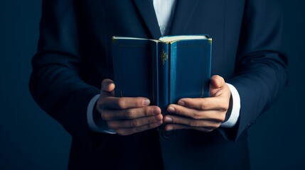 Elegant stock image of a hand holding a book, rich deep blue tones enhancing the mood of intellectual engagement - obrazy, fototapety, plakaty