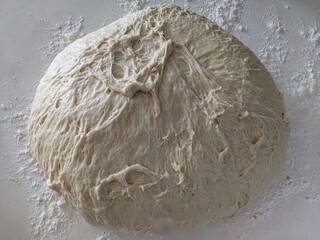 A large ball of raw dough on a floured counter