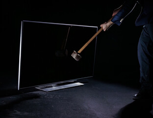 Man hitting a big flat TV screen with a sledgehammer, isolated on a black background, slow motion...