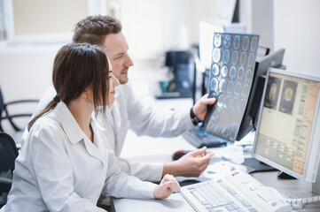 Doctors in the MRI room sit at a computer monitoring the progress of the procedure. A council of doctors examines an MRI image. Blurred image