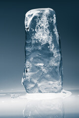 Crystal clear frosty textured natural ice block on shining mirroring surface with reflection.