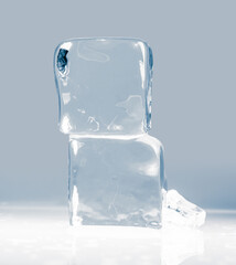Natural crystal clear melting ice cubes on a light gray background.