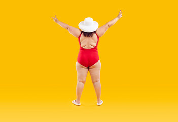 Fototapeta na wymiar Full length view behind fat woman with skin folds on back wearing red swimsuit and white summer sunhat does peace gesture standing isolated on orange yellow studio background Beach holiday fun concept