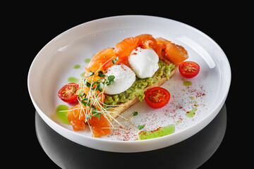 poached egg toast with avocado and salmon on a white plate