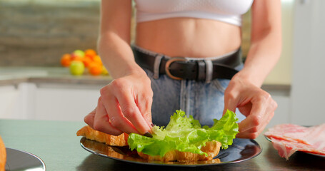 Woman making croissant sandwich with bacon and lattice