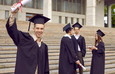 Happy male student having fun on graduation day. Portrait of joyful young man in academic hat and...