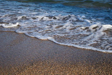Llevant beach, Barcelona, Spain, on a sunny day, waves and sea, blue sky, sand, pebbles and rocks, summer vibes