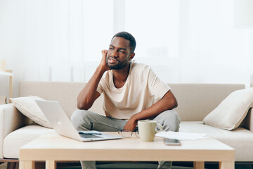 Tired African American Man Working on Laptop in Home Office Depressed Freelancer Experiencing...