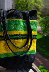 Women's bag against the background of trees. Handmade raffia beach bag.