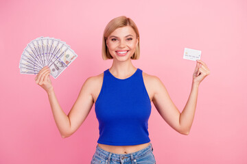Portrait of nice young girl hold money bills debit card wear blue top isolated on pink color...