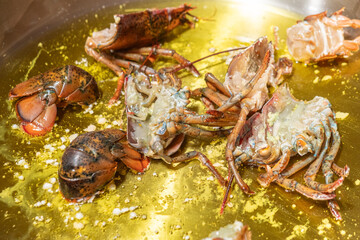 pieces of lubrigant lobster in a with oil and garlic to prepare a seafood rice recipe. Paella