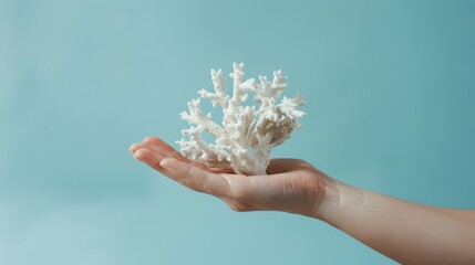 Ad shot of a hand with a piece of coral, pastel cyan background, minimalist, studio lighting,