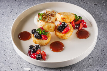 cottage cheese pancakes with berries and jam on a white plate