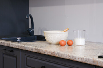 Home kitchen interiorBowl with dough, eggs and bowl of sugar on kitchen table in modern kitchen.