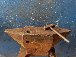 Used by blacksmiths for working metals. Old anvil and hammer in a forge.
