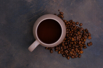 Cup glass of coffee and coffee beans on dark brown background.