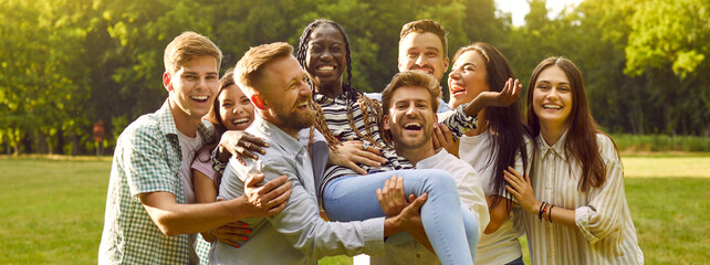 Group of happy, diverse, multiracial friends having fun in a green sunny summer park. Several...