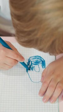 Little boy colors doughnut with blue marker in exercise book