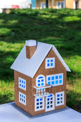 Beautiful toy two-story house with blue light in the windows on a background of green grass