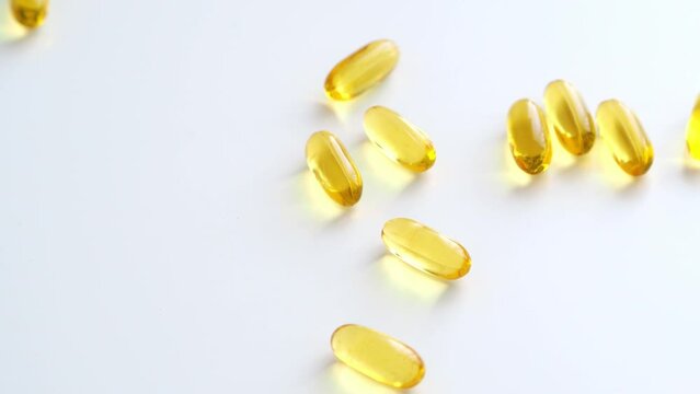 Sprinkle fish oil dietary supplements on a white background. Yellow transparent capsules. Omega 3, vitamin D, krill oil. Replenishing the deficit. Health care and control - biohacking