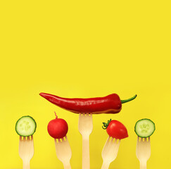 Pepper, tomato, cucumber and radish on wooden disposable forks, close-up, yellow background. Healthy eating concept. Fresh vegetables in the diet. Vegetables on a black background. Space for text