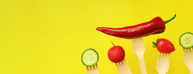 Pepper, tomato, cucumber and radish on wooden disposable forks, close-up, yellow background. Healthy eating concept. Fresh vegetables in the diet. Vegetables on a black background. Space for text