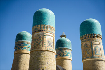 Four cupolas of Chor Minor Madrasah of Khalif Niyaz-kul and artificial stork nest in Bukhara, a popular UNESCO World Heritage tourist destination in Uzbekistan - obrazy, fototapety, plakaty