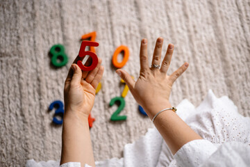 young woman holding multi-colored wooden numbers in her hands