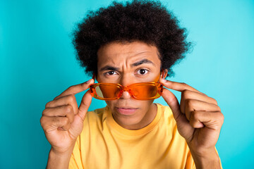 Photo of suspicious minded guy with afro hairdo dressed yellow t-shirt eyebrow up touch glasses...