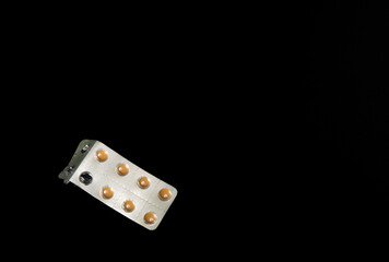 Medicine tablets packaged in blister packs of orange tablets on black background with space for text
