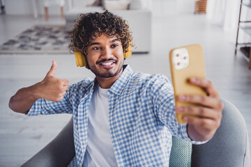 Photo of handsome cheerful guy dressed plaid shirt enjoying music tacking selfie device showing...