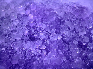 High angle violet ice heap pattern background. Pieces of crushed ice cubes in purple light....